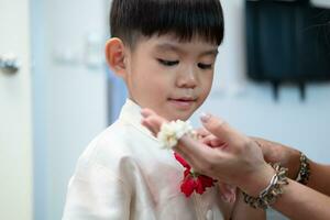 wenig asiatisch Junge geben ein Jasmin Girlande zu Mutter auf Thailands National Mutter Tag foto
