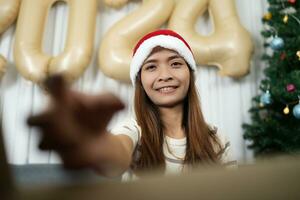 fröhlich Weihnachten 2024 Konzept asiatisch Frau öffnet Box und Picks oben Geschenk im Weihnachten Box foto