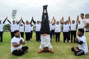 Neu Delhi, Indien, Juni 21, 2023 - - Gruppe Yoga Übung Session zum Menschen beim Yamuna Sport Komplex im Delhi auf International Yoga Tag, groß Gruppe von Erwachsene Teilnahme Yoga Klasse im Kricket Stadion foto