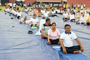 Neu Delhi, Indien, Juni 21, 2023 - - Gruppe Yoga Übung Session zum Menschen beim Yamuna Sport Komplex im Delhi auf International Yoga Tag, groß Gruppe von Erwachsene Teilnahme Yoga Klasse im Kricket Stadion foto