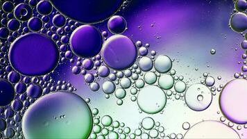 Abstraktes buntes Speiseöl lässt Blasen und Kugeln fallen, die auf der Wasseroberfläche fließen foto
