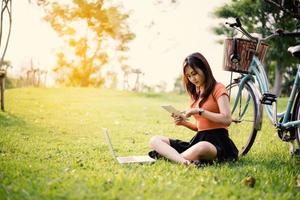 Frau mit Tablet und Laptop im Park, Outdoor-Konzept, Entspannungskonzept, Technologiekonzept foto