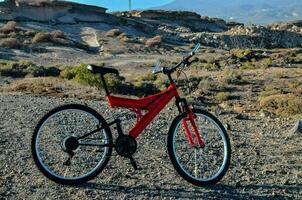 ein rot Fahrrad geparkt im das Mitte von ein Wüste foto