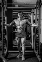 gut aussehend Mann mit groß Muskeln, posieren beim das Kamera im das Fitnessstudio foto