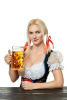 jung bayerisch Frau im dirndl Sitzung beim Tabelle mit Bier auf Weiß Hintergrund foto