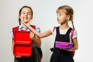 Schüler von primär Schule mit Lunchboxen im Hände. Mädchen mit Rucksäcke sind Essen Frucht. Anfang von Unterricht. zuerst Tag von fallen. foto