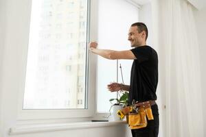 Heimwerker mit ein schnurlos Schraubendreher zu Installieren ein Fenster handhaben. qualifiziert Arbeiter Dienstleistungen, Zuhause Reparatur und Renovierung. foto