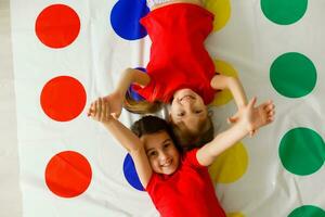 zwei glücklich Mädchen im Kinder- Kleider begeistert abspielen auf das Boden. foto