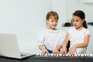 Zuhause Klavier Lektion. zwei Mädchen trainieren Blatt Musik- auf einer Musical Instrument. Familie Konzept. das Idee von Aktivitäten zum Kinder während Quarantäne. foto