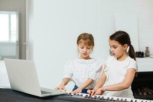 Zuhause Klavier Lektion. zwei Mädchen trainieren Blatt Musik- auf einer Musical Instrument. Familie Konzept. das Idee von Aktivitäten zum Kinder während Quarantäne. foto