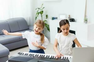 Zuhause Klavier Lektion. zwei Mädchen trainieren Blatt Musik- auf einer Musical Instrument. Familie Konzept. das Idee von Aktivitäten zum Kinder während Quarantäne. foto