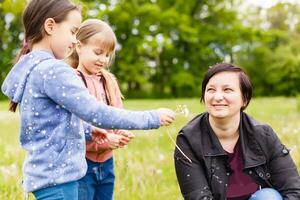 Mutter mit kleiner Tochter weht zu Löwenzahn - Lebensstil im Freien Szene im Park foto