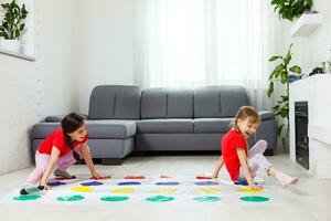 zwei glücklich Mädchen im Kinder- Kleider begeistert abspielen auf das Boden. foto