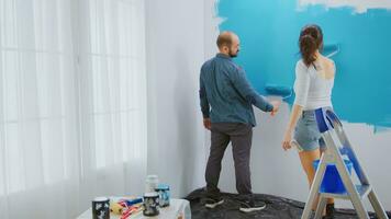 kaukasisch Paar Gemälde Mauer mit Walze Bürste und Blau malen. Wohnung Renovierung und Zuhause Konstruktion während renovieren und Verbesserung. Reparatur und dekorieren. foto