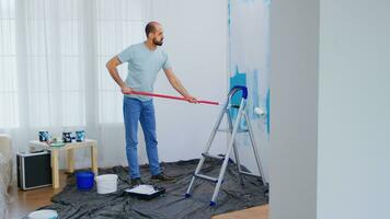 maskieren Blau Farbe mit Walze Bürste eingetaucht im Weiß malen. Heimwerker renovieren. Wohnung Renovierung und Zuhause Konstruktion während renovieren und Verbesserung. Reparatur und dekorieren. foto