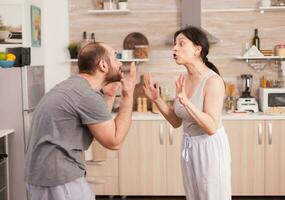 Paar schreiend beim jeder andere im das Küche im das Morgen. jung Paar Streit im das Küche. Mann und Frau Geschrei im Frustration während Zuhause Gespräch. foto