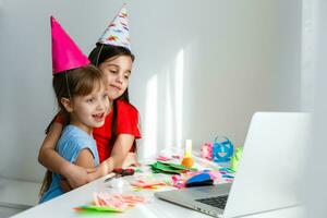 ein wenig Mädchen, Kurven und lacht im Vorderseite von ein Laptop im ein Deckel. feiert Geburtstag über Internet im Quarantäne Zeit, Selbstisolation und Familie Werte, online Geburtstag. Herzliche Glückwünsche zu das Animator foto