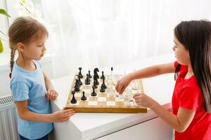 zwei wenig Schwester spielen Schach beim Zuhause foto