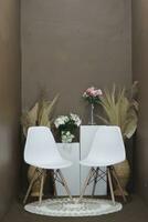Hintergrund zum Fotos im das Foto Studio mit ein braun Thema und ästhetisch Weiß Stühle dekoriert mit künstlich Blumen