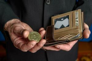 ein Mann im ein passen hält ein Bitcoin und ein Brieftasche im seine Hand. foto