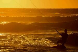 ein Mann Kitesurfen im das Ozean beim Sonnenuntergang foto