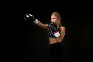 schön weiblich Athlet im Boxen Handschuhe, im das Studio auf ein schwarz Hintergrund. foto