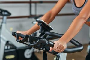 Frau Hände auf ein Bar stationär Fahrrad das Fitnessstudio foto