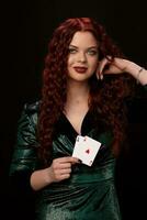 sexy rothaarig Frau posieren mit ein spielen Karten im ihr Hände, auf schwarz Hintergrund foto