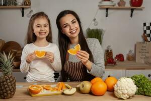 Mutter und ihr Tochter sind tun ein Obst Schneiden und haben Spaß beim das Küche. foto