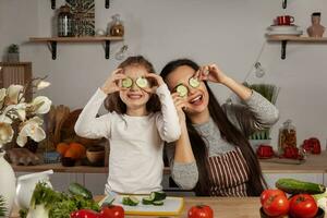 Mutter und ihr Tochter sind Herstellung ein Gemüse Salat und haben Spaß beim das Küche. foto