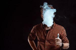junger mann, der elektronische zigarette raucht foto