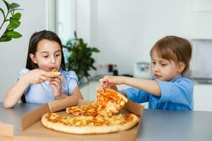 zwei lächelnd Mädchen Essen Pizza Scheiben beim Zuhause foto