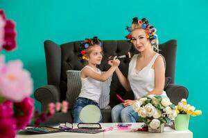 Mama und Tochter im das Studio auf das Sofa im das Lockenwickler machen oben und haben Spaß foto