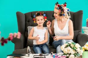 Mama und Tochter im das Studio auf das Sofa im das Lockenwickler machen oben und haben Spaß foto