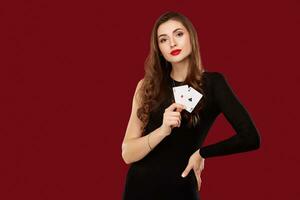 schön kaukasisch Frau im schwarz Kleid mit Poker Karten Glücksspiel im Kasino foto