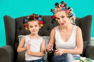 Mama und Tochter im das Studio auf das Sofa im das Lockenwickler machen oben und haben Spaß foto