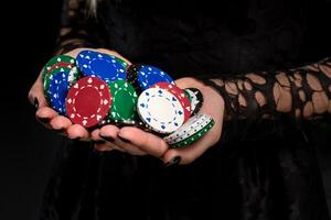 elegant weiblich Kasino Spieler halten ein Hand voll von Chips auf schwarz Hintergrund, Hände schließen oben foto