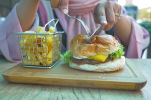 Frauen Essen Cheeseburger serviert mit Fritten auf Tabelle foto