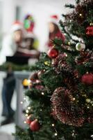 schließen oben Fokus Schuss auf Büro Weihnachten Baum im festlich dekoriert Arbeitsplatz mit Geschäft Mitarbeiter Arbeiten im das Hintergrund. Weihnachten aufwendig Unternehmen Arbeitsplatz während Winter Urlaub Jahreszeit foto