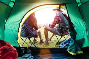männliche und weibliche Camper unterhalten sich vor dem Campingzelt. Menschen und Lebensstile Konzept. Picknick- und Reisekonzept. Natur im Sommerthema. Rückansicht und Innenzeltwinkel foto