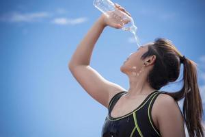 Sportmädchen, das sich Wasser ins Gesicht gießt, wenn es sich ausruht oder eine Pause macht, sich entspannen und Sportkonzept foto