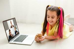 erziehen beim heim. Kind Mädchen machen Hausaufgaben mit Haustier Hamster. komisch Ingwer Hamster Sitzung auf Tabelle wo Kind ist Schreiben. zurück zu Schule. foto