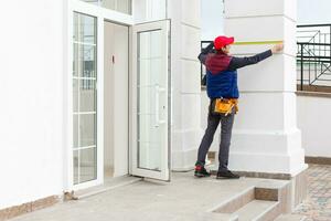 ein Arbeiter installiert Paneele Beige Abstellgleis auf das Fassade von das Haus foto