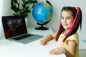 cool online Schule. Kind studieren online beim Zuhause mit ein Laptop. heiter jung wenig Mädchen mit Laptop Computer studieren durch online E-Learning System. Entfernung oder Fernbedienung Lernen foto