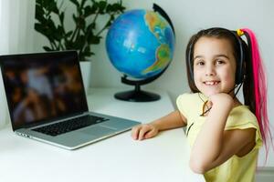 süß wenig Mädchen mit Laptop beim heim. Ausbildung, online lernen, Zuhause studieren, Entfernung Lernen, Schülerin Kinder Lebensstil Konzept foto