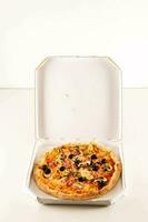 ein Pizza im ein Weiß Box auf ein Weiß Oberfläche foto