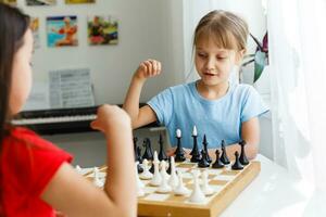 zwei wenig Schwester spielen Schach beim Zuhause foto