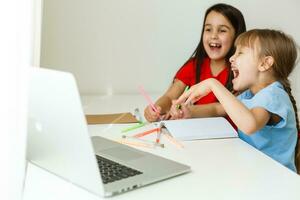 cool online Schule. Kinder studieren online beim Zuhause mit ein Laptop. heiter jung wenig Mädchen mit Laptop Computer studieren durch online E-Learning System. Entfernung oder Fernbedienung Lernen foto