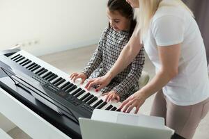 Frau, die ihrer Tochter beim Klavierspielen half, Körper und Knöpfe des Klaviers wurden digital modifiziert foto