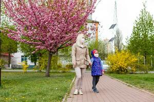 Mutter und Tochter mit Masken Gehen und reden auf das Straße foto